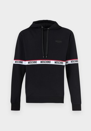 Fekete kapucnis pulóver hosszú ujjakkal, első zsebbel, valamint "Moschino" felirattal, amely fehér csíkon ismétlődik a mellkason és a karokon, kapucni húzózsinórokkal.