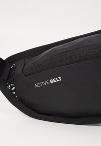 Svart aktivt bälte med en slät, texturerad yta, nylondragkedjeficka och nätaccenter. "ACTIVE BELT"-logotypen visas tydligt.