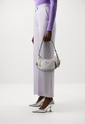 Silver nylon handväska med rundad form och två dragkedjefack, hålls i en hand. Bärs med ljuslila vida byxor och silverfärgade klackar.