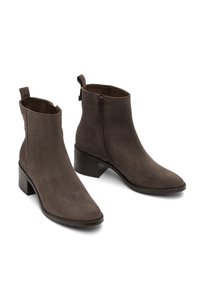 Stivaletti in suede marrone con punta affusolata e tacco a blocco. Presentano una cerniera laterale e un soffietto sul retro per facilitarne l'indossamento.