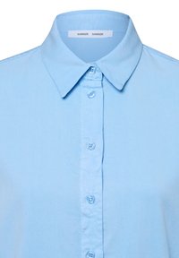 Light blue button-up shirt, cotton fabric, featuring a classic collar and six buttons down the front. Tag reads "SAMSØE SAMSØE."