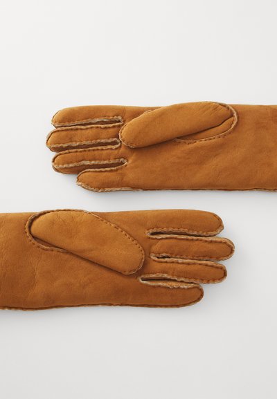 Guanti in suede marrone con quattro dita e un pollice. Cuciture in pelle visibili lungo i bordi; texture morbida con una finitura liscia.