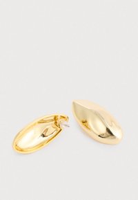 Et par blanke guld ovale clips-øreringe, hvor den ene viser bagsiden med en klar plastikklips, og den anden viser den polerede forsides overflade.