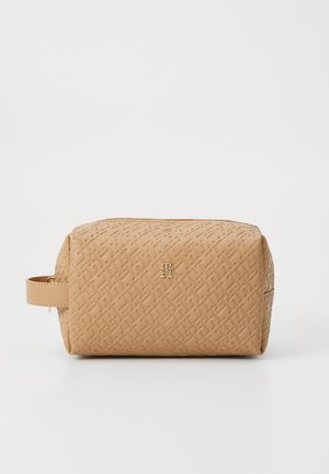 Tan, textured cosmetic bag with a geometric pattern, featuring a zipper closure and a side handle. Gold hardware logo accent on the front.