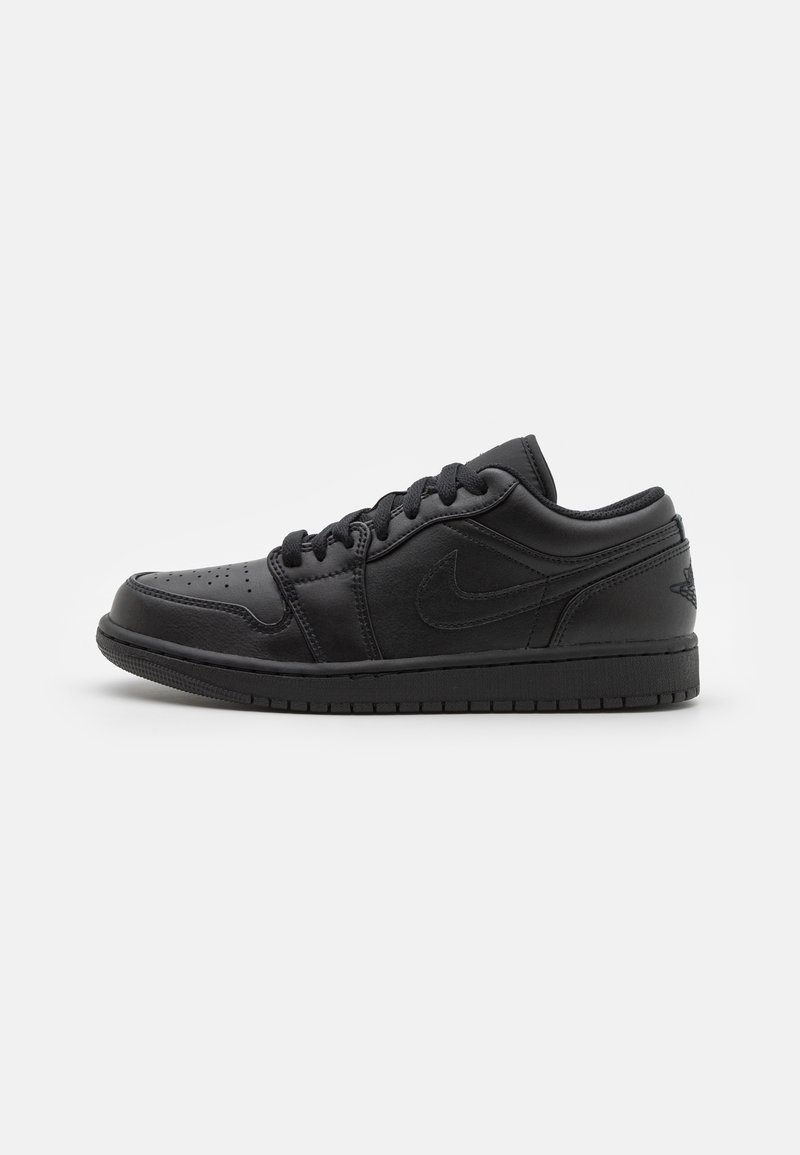 Baskets basses en cuir noir avec lacets noirs et semelle texturée, présentant des logos embossés discrets sur les côtés et le talon.