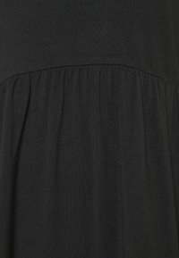 Svart klänning med en figursydd överdel och en rynkad kjol. Tyget är mjukt med en lätt stretch, vilket skapar en slät textur och fall.