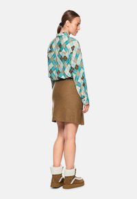 Plaid, long-sleeved shirt with blue, brown, and turquoise colors; brown, knee-length skirt; brown boots with white accents and fur lining.