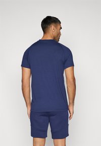 Marineblå kortærmet t-shirt med rund halsudskæring og raglanærmer, parret med matchende shorts med et tekstureret mønster.