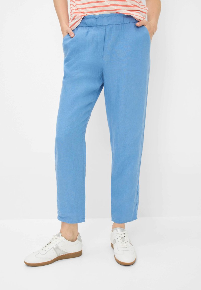 Lichtblauwe, lichte broeken met een elastische tailleband, zijzakken en een rechte pijpdesign, gedragen met witte sneakers.