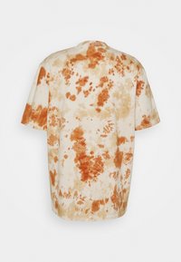 Tričko s krátkým rukávem s oranžovým a béžovým tie-dye vzorem na bílém pozadí, zobrazené ze zadní strany.