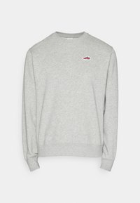 Grå sweatshirt i mjukt, texturerat tyg med långa ärmar och rund halsringning. Har en liten, röd sneakerlogga på bröstet.