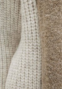 Light beige knitted fabric and a textured brown fabric, showcasing contrasting materials and colors with a soft appearance.