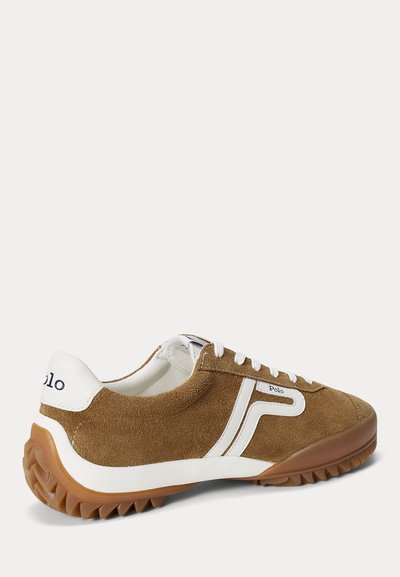 Baskets en daim marron avec lacets blancs, bande blanche style Puma, marquage "Polo" et semelle en caoutchouc marron texturée.