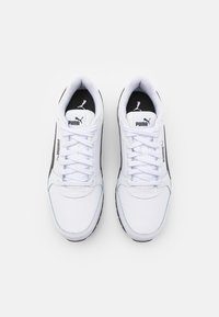 Chaussures de sport blanches avec accents noirs, disposant d'une tige synthétique lisse, d'un bout arrondi, de lacets plats et d'une semelle en caoutchouc texturée.