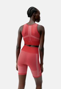 Rotes sportliches Crop-Top und Shorts-Set aus strukturiertem, figurbetontem Material mit kontrastierenden weißen Nähten und ausgearbeitetem Paneeldesign.