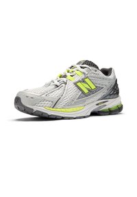 Γκρι και λευκό αθλητικό παπούτσι με ύφασμα από δίχτυ, ανάγλυφες λεπτομέρειες, φωτεινές κίτρινες λεπτομέρειες και μαύρα χαρακτηριστικά. Ελαστική σόλα με ανάγλυφο μοτίβο.