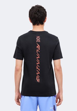 Άνδρας που φοράει μαύρο μπλουζάκι Nike Running με κάθετο πορτοκαλί λογότυπο και ανοιζoύ μπλε σορτς Nike, εμφανιζόμενος από πίσω.