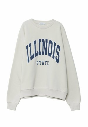 Jasnobeżowa bluza crewneck z długimi rękawami, z napisem „ILLINOIS STATE” dużymi granatowymi literami na przodzie.