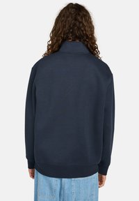 Marineblauwe sweatshirt met een hoge kraag, lange mouwen en ribgebreide manchetten. Zachte textuur en ontspannen pasvorm, met een minimalistisch ontwerp.
