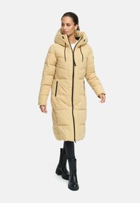 Long beige puffer coat with a hood, featuring a full-length zipper and black accents. Smooth texture, quilted pattern, and two side pockets.