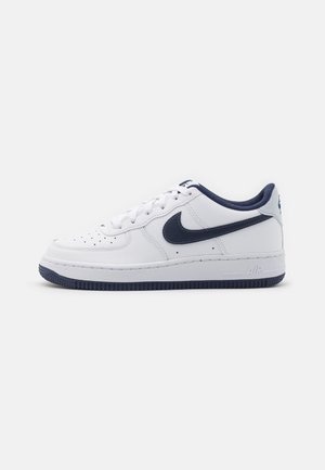 Baskets basses Nike Air Force 1 blanches et bleu marine avec lacets et perforations sur l’orteil, présentées sur un fond clair uni.