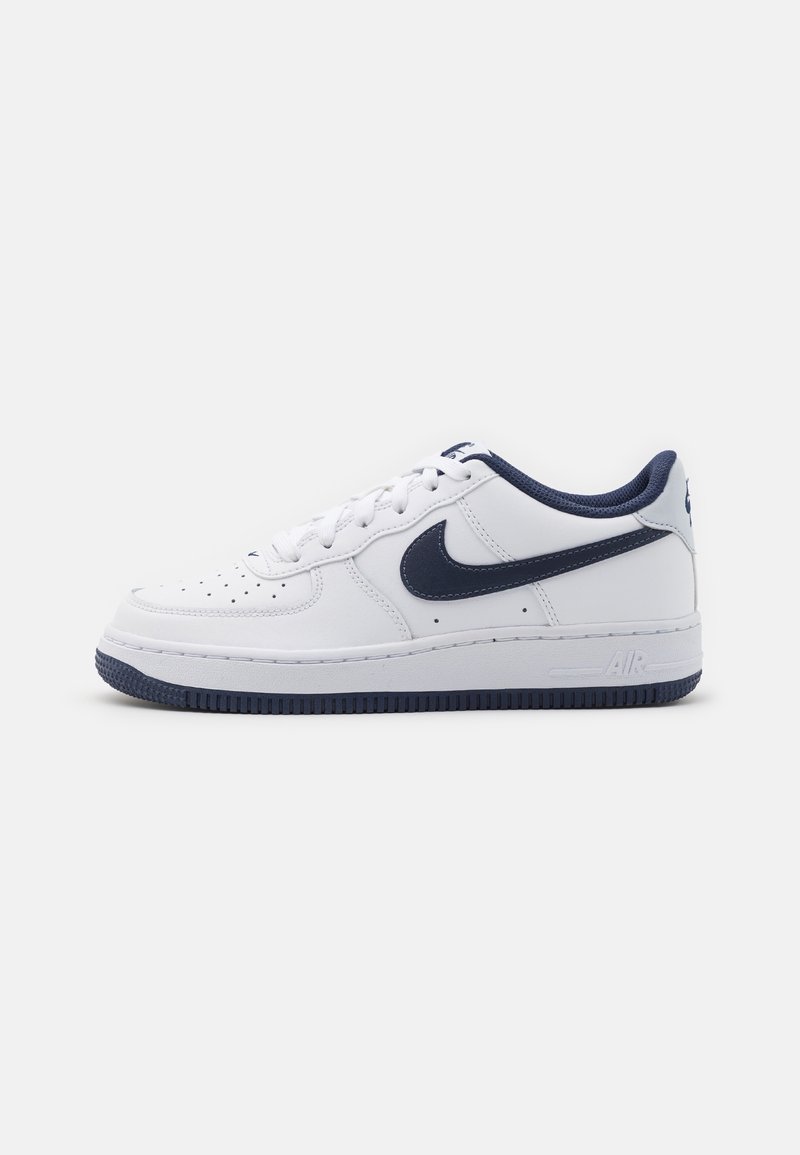Baskets basses Nike Air Force 1 blanches et bleu marine avec lacets et perforations sur l’orteil, présentées sur un fond clair uni.