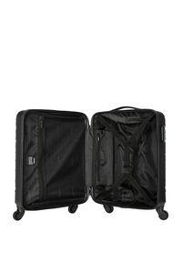 Valise rigide noire avec quatre roues, compartiments en maille et en tissu à l'intérieur, sangles croisées pour les objets, poche zippée, design épuré.