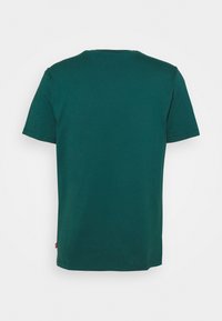 T-shirt en coton turquoise avec un col rond et des manches courtes. Texture lisse et coupe décontractée. Vue de dos sans marque ni motif visible.