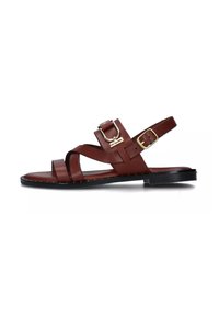 Sandal in pelle marrone con tacco piatto, cinturini incrociati e dettaglio con fibbia laterale. Presenta una texture liscia e un design open-toe.