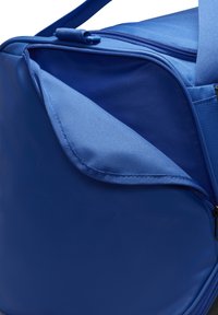 Blauwe reistas met een gestructureerd oppervlak, voorzien van een ritszak en stevige stoffenhengsels. Inclusief een gladde voering en contrasterende stiknaad.