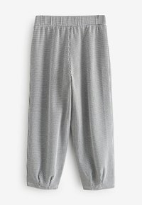 Pantalones cortos de cuadros en blanco y negro con una cinturilla elástica, que presentan detalles fruncidos en las piernas y una textura de tela suave.