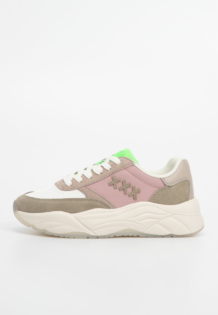 Lage sneaker met beige suède, roze stoffen panelen, witte veters, dikke witte zool en neon groene tongdetail, weergegeven op een witte achtergrond.
