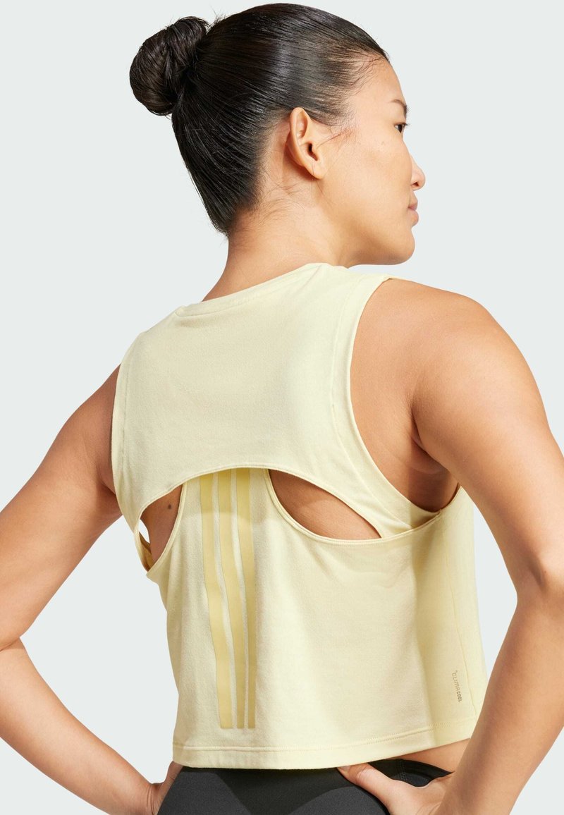 Top corto amarillo con espalda cortada y rayas verticales, hecho de una tela suave; cuenta con un cuello redondo y un ajuste relajado.