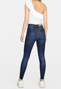 Donkerblauwe denim skinny jeans met een hoge taille, met een klassieke vijf-pocket ontwerp en een subtiele vervaagde textuur.