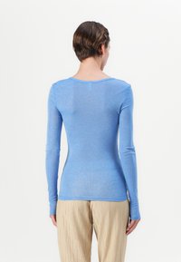 Langärmliges, enganliegendes Oberteil in Hellblau, aus weichem Stoff. Verfügt über einen weit geschnittenen Ausschnitt und nahtloses Design an Schultern und Bündchen.