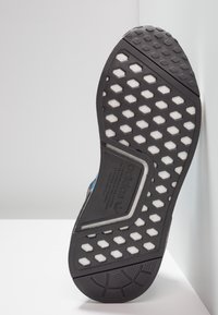 Svart gummisula för sneakers med hexagonal skärmönster, vita skumdetaljer och Adidas-logotyp på en grå bakgrund.