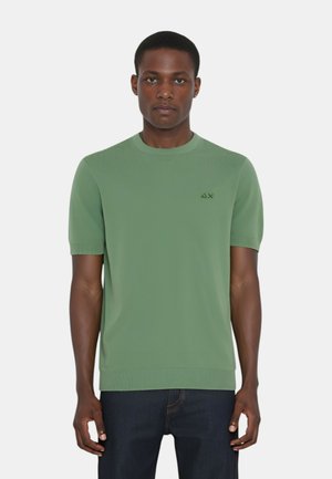 Maglione a maniche corte verde a maglia con colletto e polsini a coste, caratterizzato da un piccolo logo sul lato sinistro del petto. Texture liscia, vestibilità rilassata.