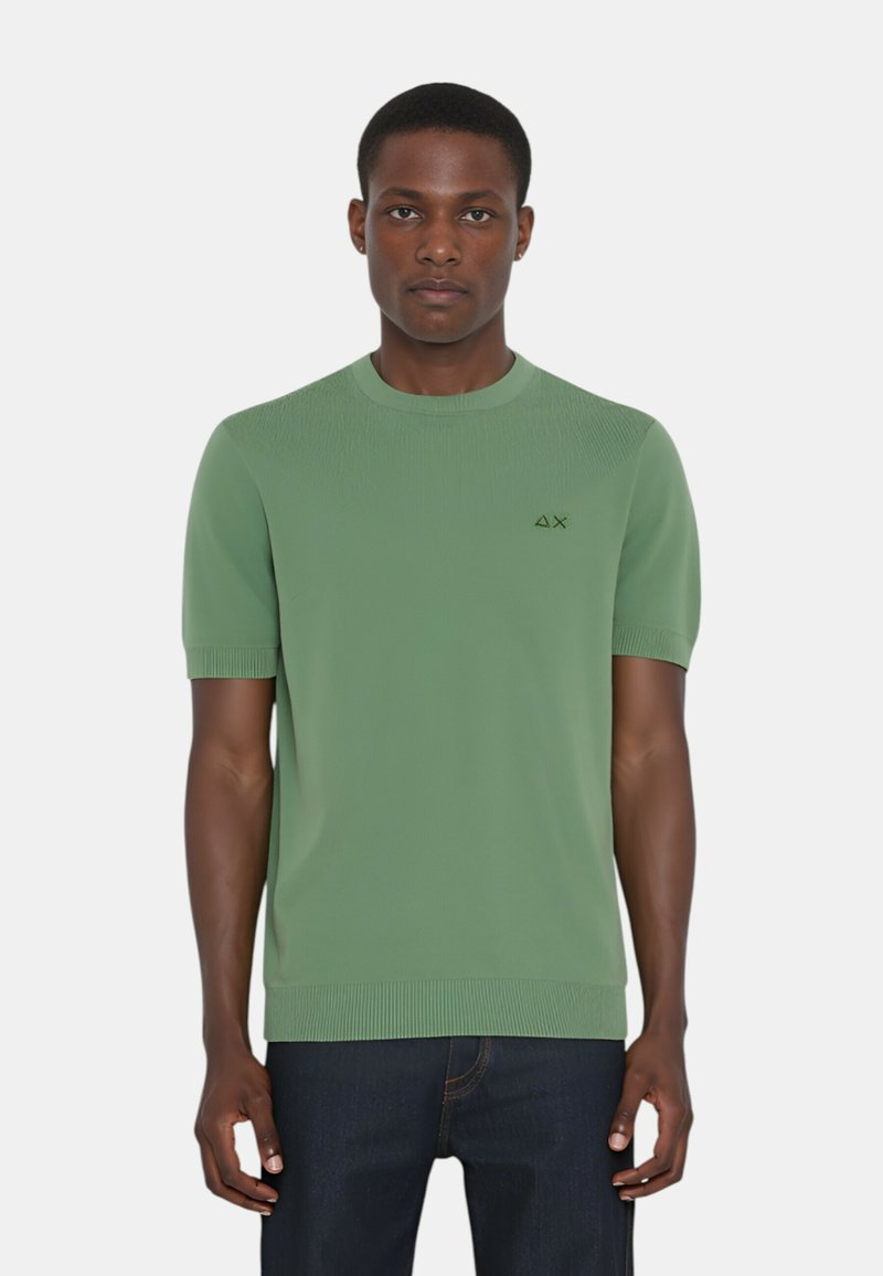 Maglione a maniche corte verde a maglia con colletto e polsini a coste, caratterizzato da un piccolo logo sul lato sinistro del petto. Texture liscia, vestibilità rilassata.