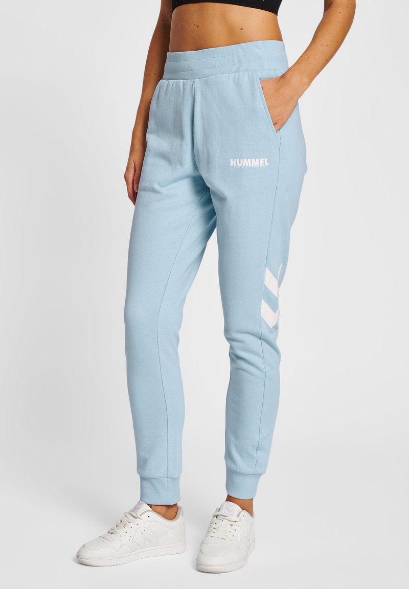 Lyseblå sweatpants med en blød tekstur, der har sidelommer og hvid logo-tekst. Taperet design med ribkant ved anklerne og chevronmønster detaljer.