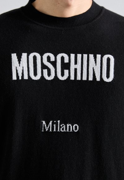 Schwarzer Pullover mit großer, weißer "MOSCHINO"-Schrift über der Brust und kleinerem "Milano"-Logo darunter, mit Rundhalsausschnitt und Strickstoff.