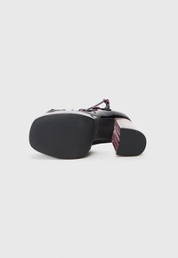 Pantofii cu toc din piele lacuită neagră, cu un toc bloc transparent, cu dungi violet. Textură netedă, cu talpă din cauciuc și detalii cu șireturi pe partea superioară.