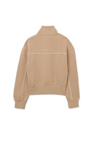 Felpa beige con colletto alto, polsini e vita a coste. Presenta piping bianchi e testo ricamato "daydream believer" sul retro.