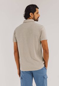 Grijze polo met korte mouwen, gemaakt van een zachte stof en voorzien van een klassieke kraag, gedragen met lichtblauwe cargoshorts. Aanpasbare pasvorm met een casual stijl.