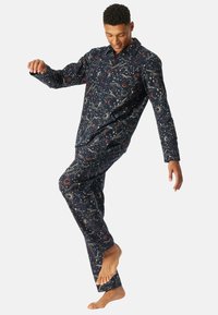Conjunto de pijama en color navy con un patrón celestial de estrellas y planetas en dorado, camisa de manga larga y pantalones a juego. Tejido de textura suave.