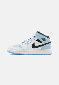 Baskets montantes en cuir blanc avec des accents bleu clair, un swoosh Nike noir et une pointe perforée. Dotées d'une semelle en caoutchouc bleue et du logo Jordan.