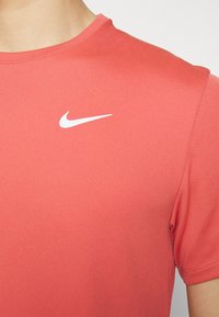 Red athletic t-shirt made of soft fabric, featuring a round neckline and short sleeves. Includes a white Nike logo on the chest.
