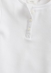 Weißes geripptes Oberteil mit Henley-Ausschnitt, ausgestattet mit vier Knöpfen und subtilen Texturdetails. Etikett sichtbar mit "next" Markenlabel.