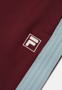 Pantalones cortos deportivos burdeos con una cinturilla elástica azul claro y el logotipo F bordado en blanco. Tejido suave con un ligero brillo.