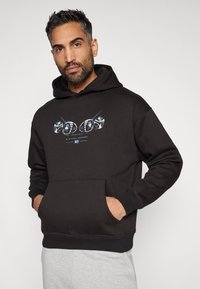 Felpa nera con cappuccio realizzata in tessuto morbido, caratterizzata da una stampa grafica sul davanti e una tasca a marsupio. Polsini e orlo a coste.