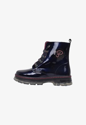 Bota de tobillo azul marino brillante con cordones, costuras rosas, suela negra y parche circular bordado en el lateral.